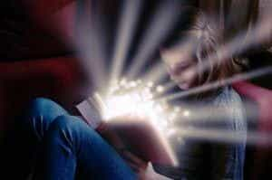 A young girl reading a book emitting sparks.