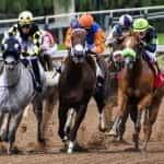 Horses racing on a dirt track.