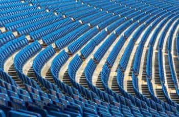 Multiple rows of blue seats at a large sports stadium.