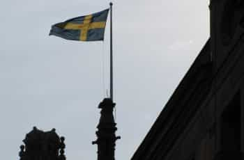 A flag hoisted at the top of a building against a blue sky.