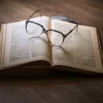 Eyeglasses sit on an open leather-bound book.