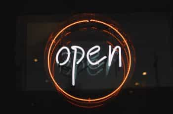 A classic open sign in neon lettering in the window of a shop or restaurant.