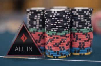 Chips and an ‘All IN’ dealer button on a poker table.