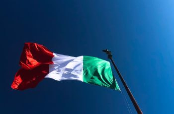 A red, white, and green flag against a blue sky.