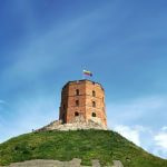 A tall brick tower on top of a grassy hill.